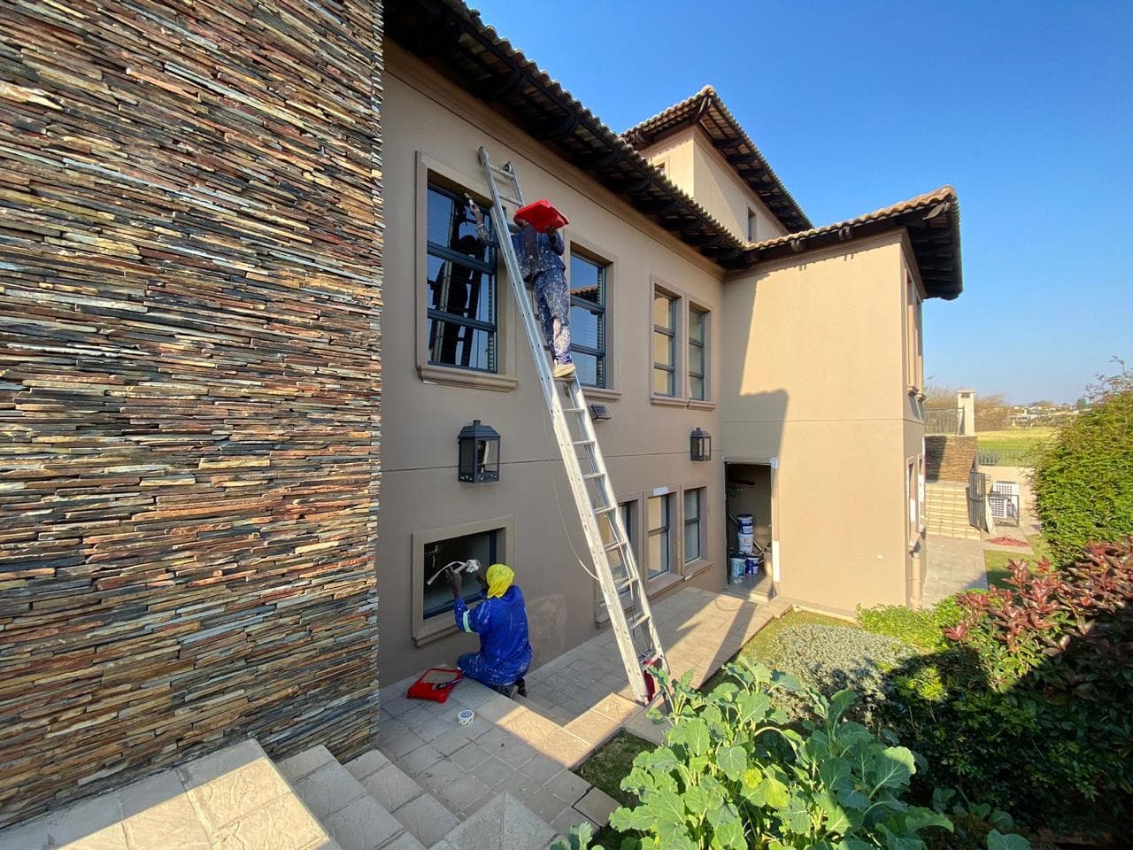 Contractors painting window trim on a two-storey home