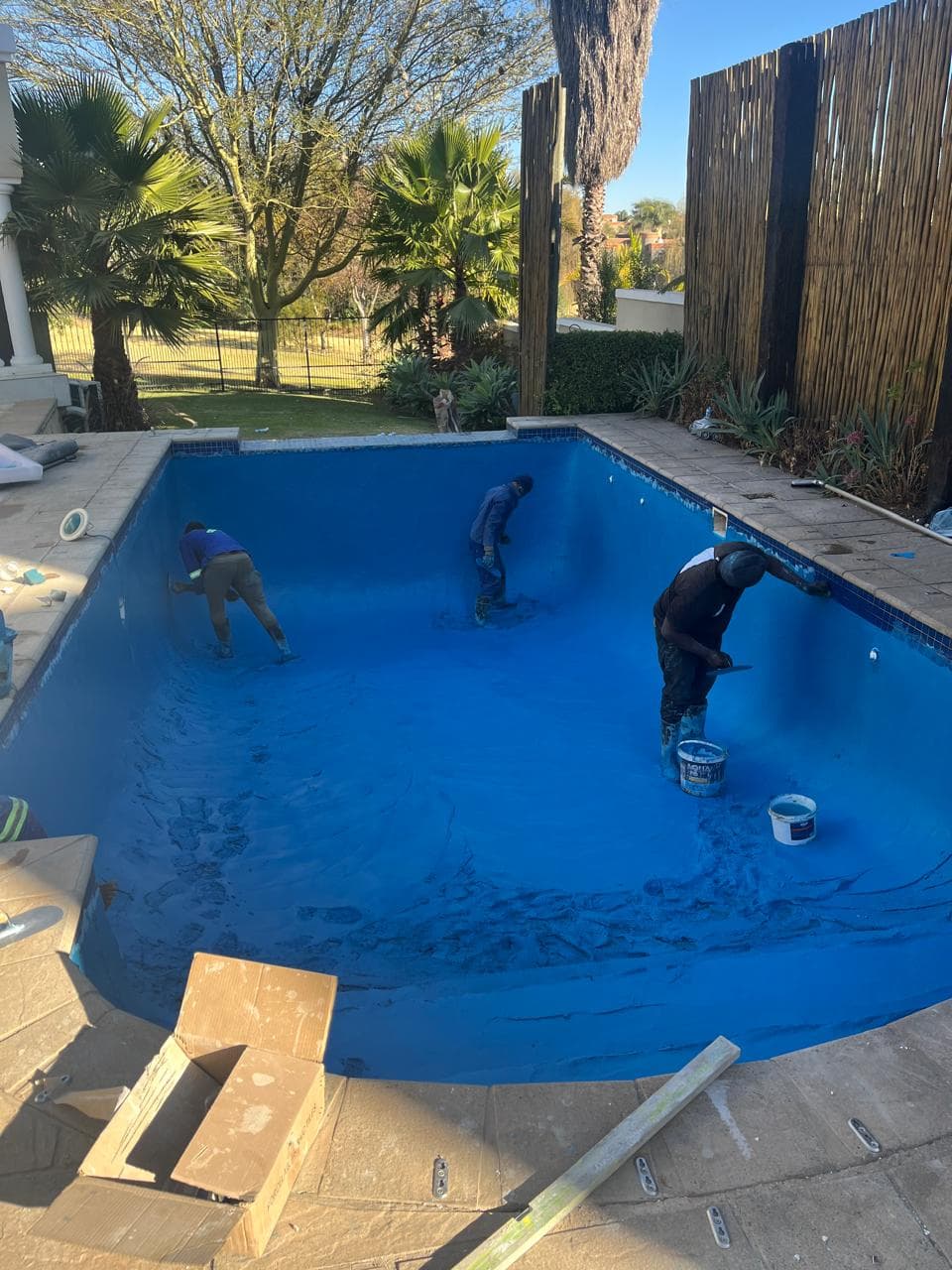 Team applying a new coating inside a drained pool