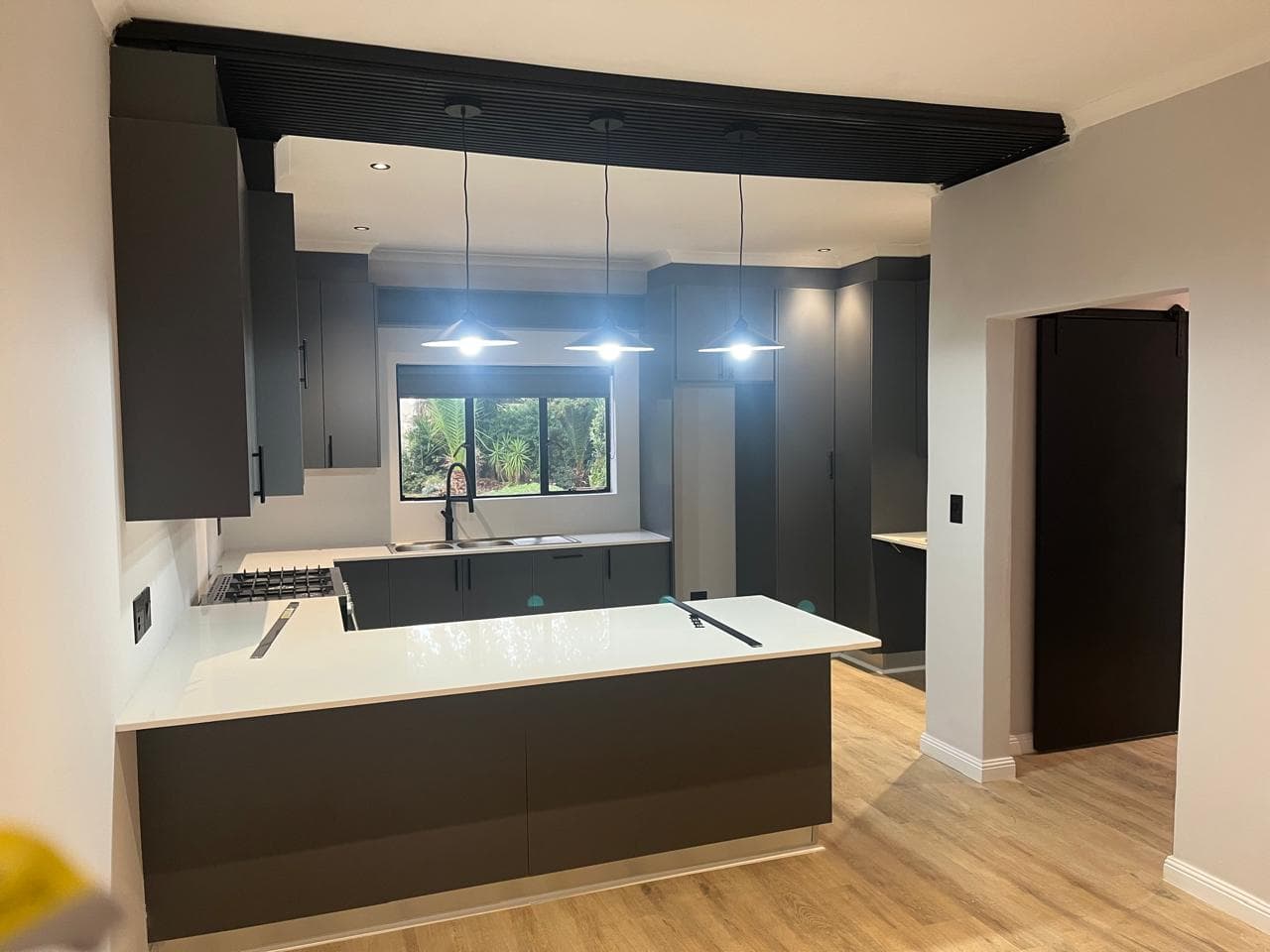 White kitchen countertops with dark cabinetry, a peninsula, and an undermount sink